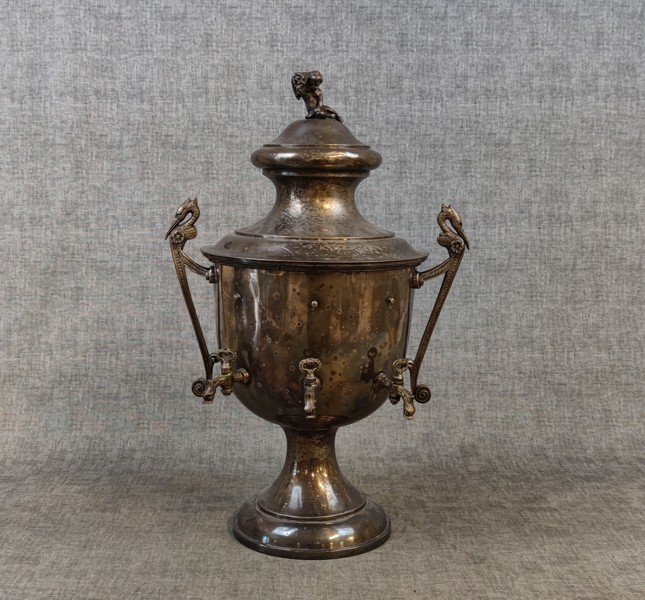 Samovar/dryckeskylare- för tre olika drycker, 1800-talets senare hälft, vitmetall, tappkranar i form av psykopompern hänklar med fågelhuvud.