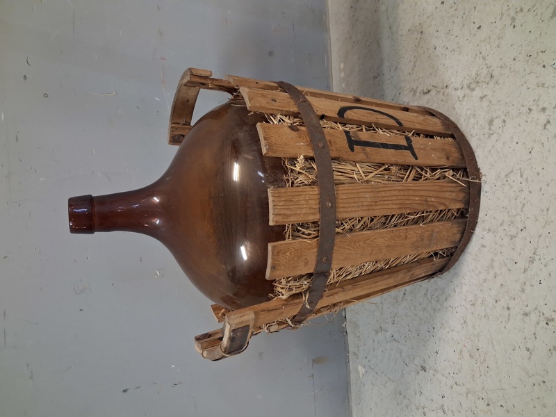 Damejeanne i rustik träkorg.